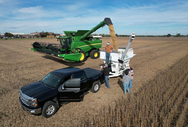 students watch combine empty grain into grain cart