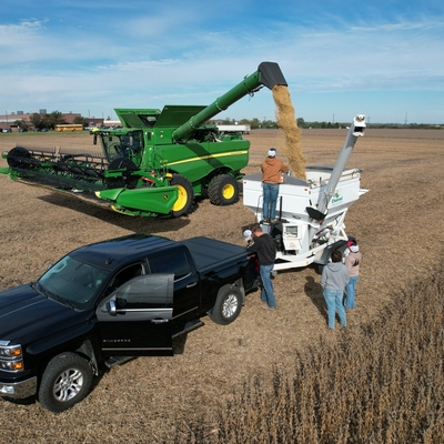 students watch combine empty grain into grain cart