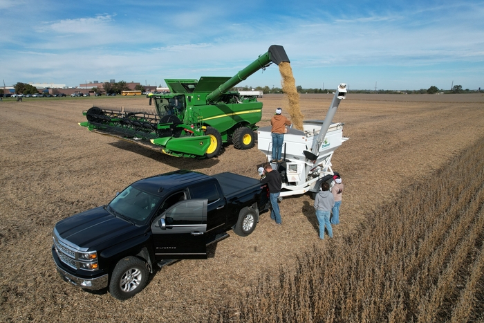 students watch combine empty grain into grain cart