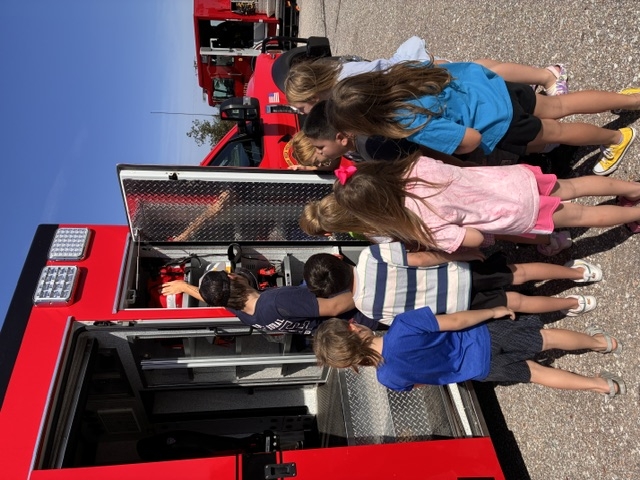 Students listen to firefighters near ambulance
