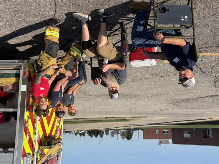 Volunteer firefighters sitting near firetruck.