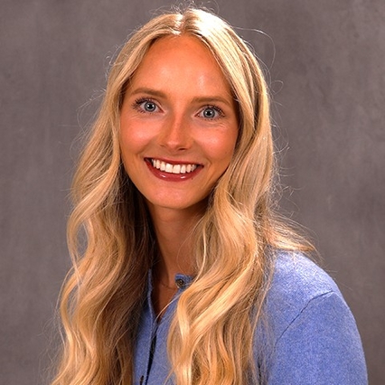 A picture of a woman in a blue cardigan with blonde hair.